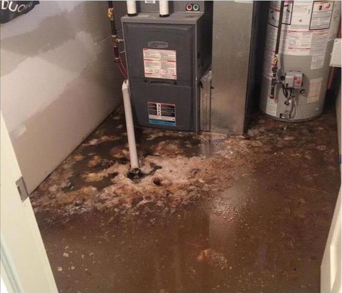 dirty floodwater on the basement floor, heavy appliances nearby