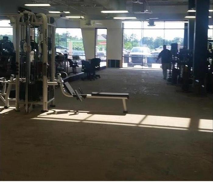 Gym with equipment and SERVPRO tech in the background 