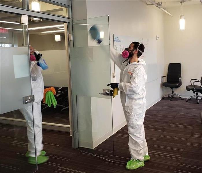 Two SERVPRO employees cleaning a glass door.